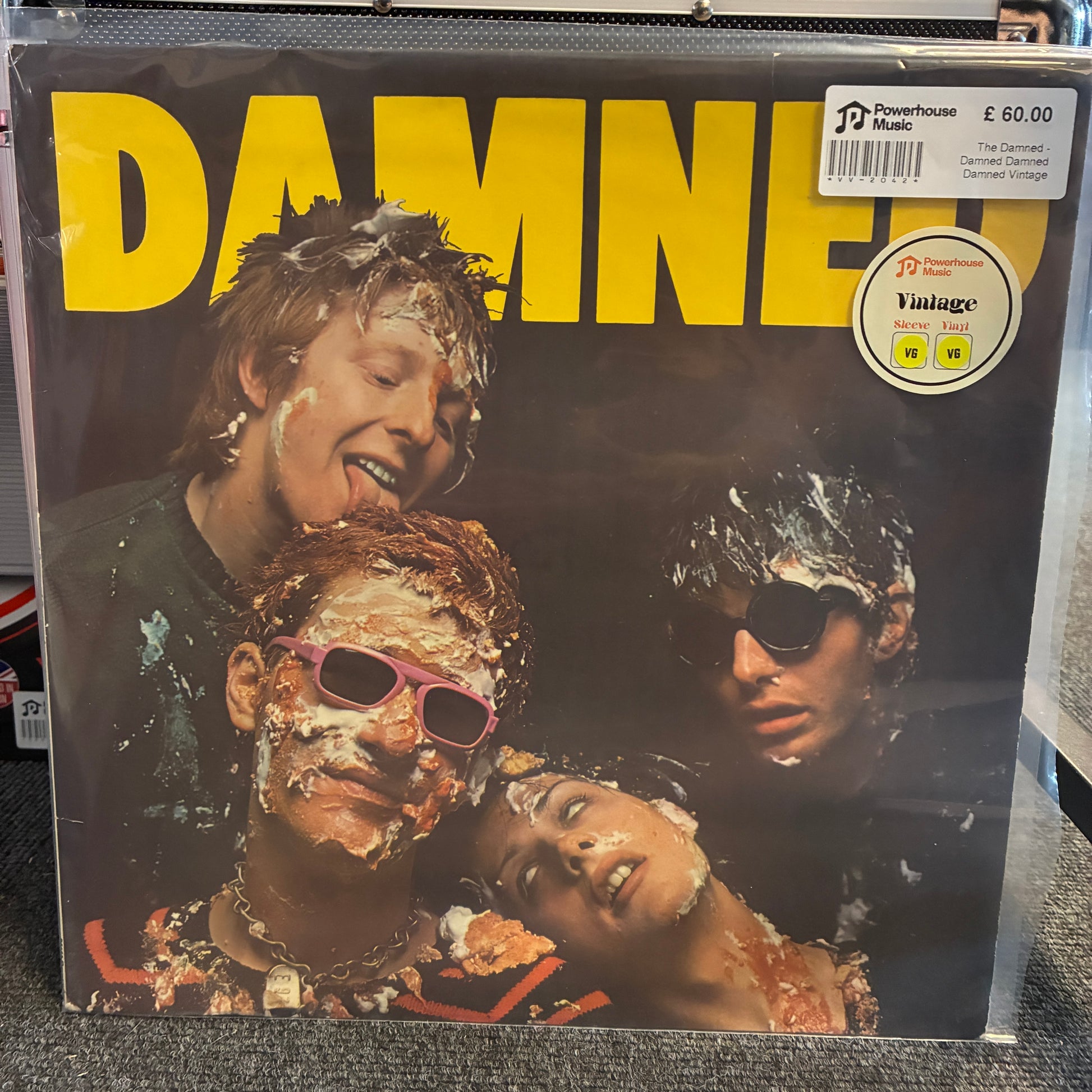 The Damned - Damned Damned Damned Vintage Vinyl LP Damned III vinyl record cover in a clear plastic sleeve, showing the band members covered in white powder with large yellow 'DAMNED' text across the top. A Powerhouse Records price sticker is visible in the upper right.