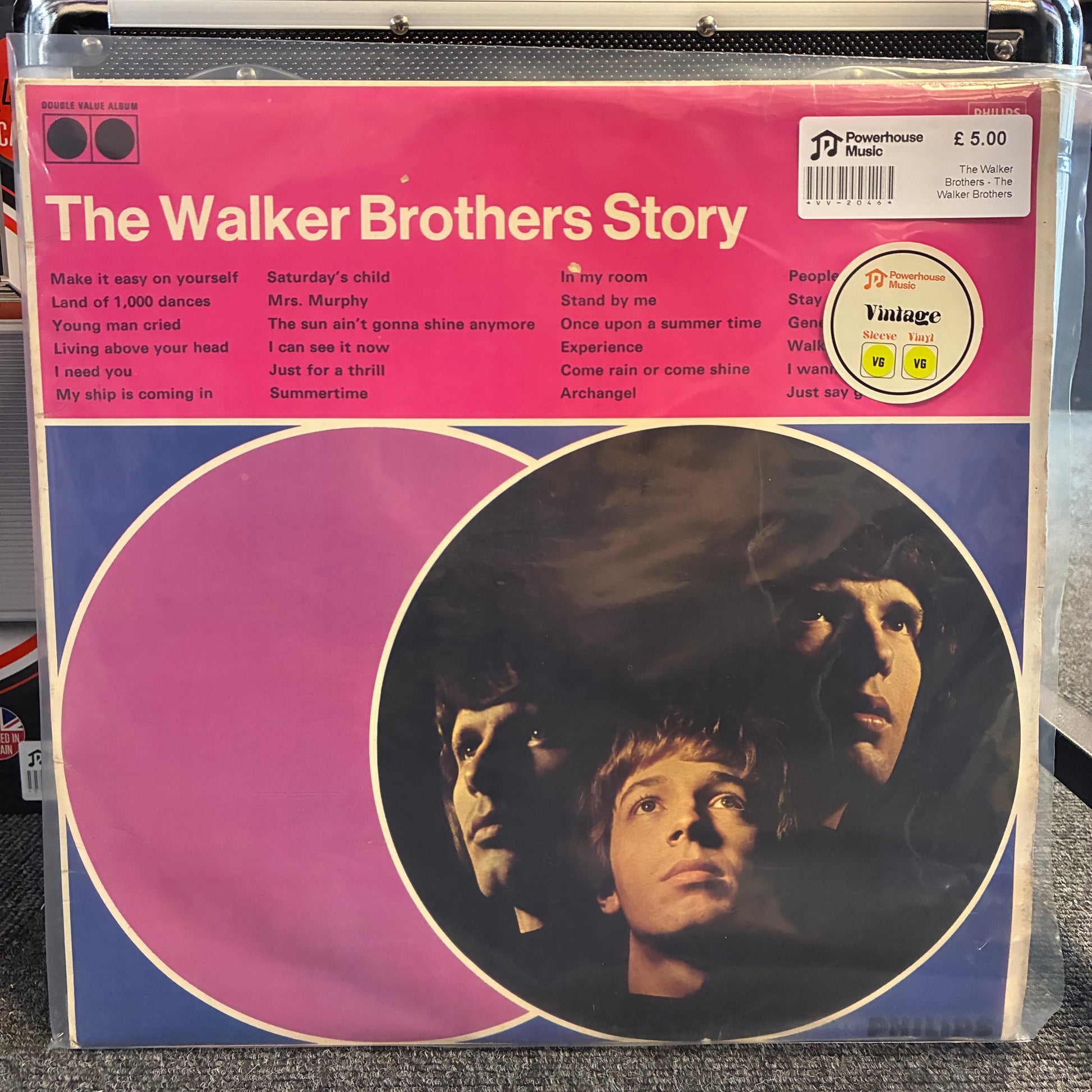The Walker Brothers - The Walker Brothers Story Vintage Vinyl LP Vinyl record sleeve for 'The Walker Brothers Story' with a pink and purple design, featuring the band members' faces in a circular graphic and a Powerhouse Music Vintage label.