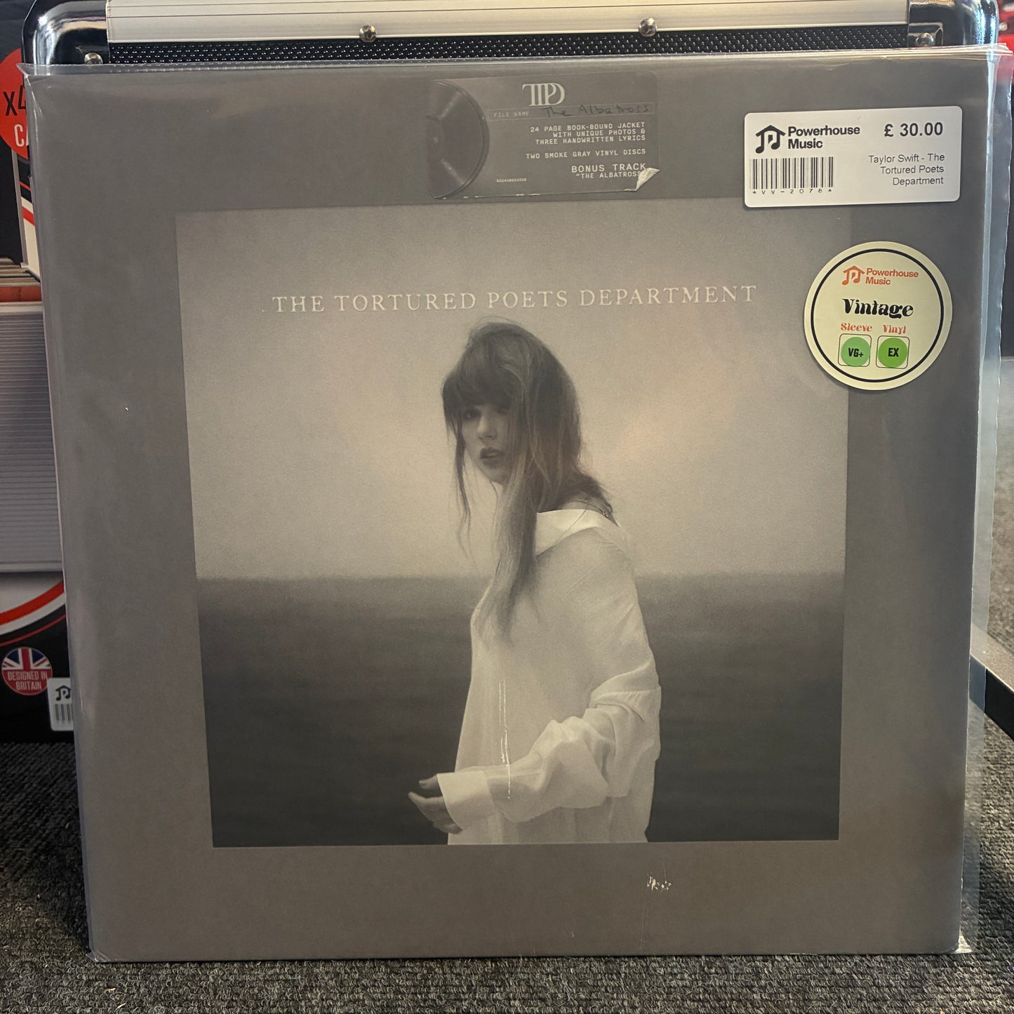 Taylor Swift - The Tortured Poets Department (Special Edition Smoke Gray) Vintage Vinyl LP A vinyl record sleeve for 'The Tortured Poets Department' by Powerhouse Music, featuring a grayscale photo of a woman in a white shirt. The sleeve is sealed in plastic with a Powerhouse Music sticker and barcode label visible on the right.