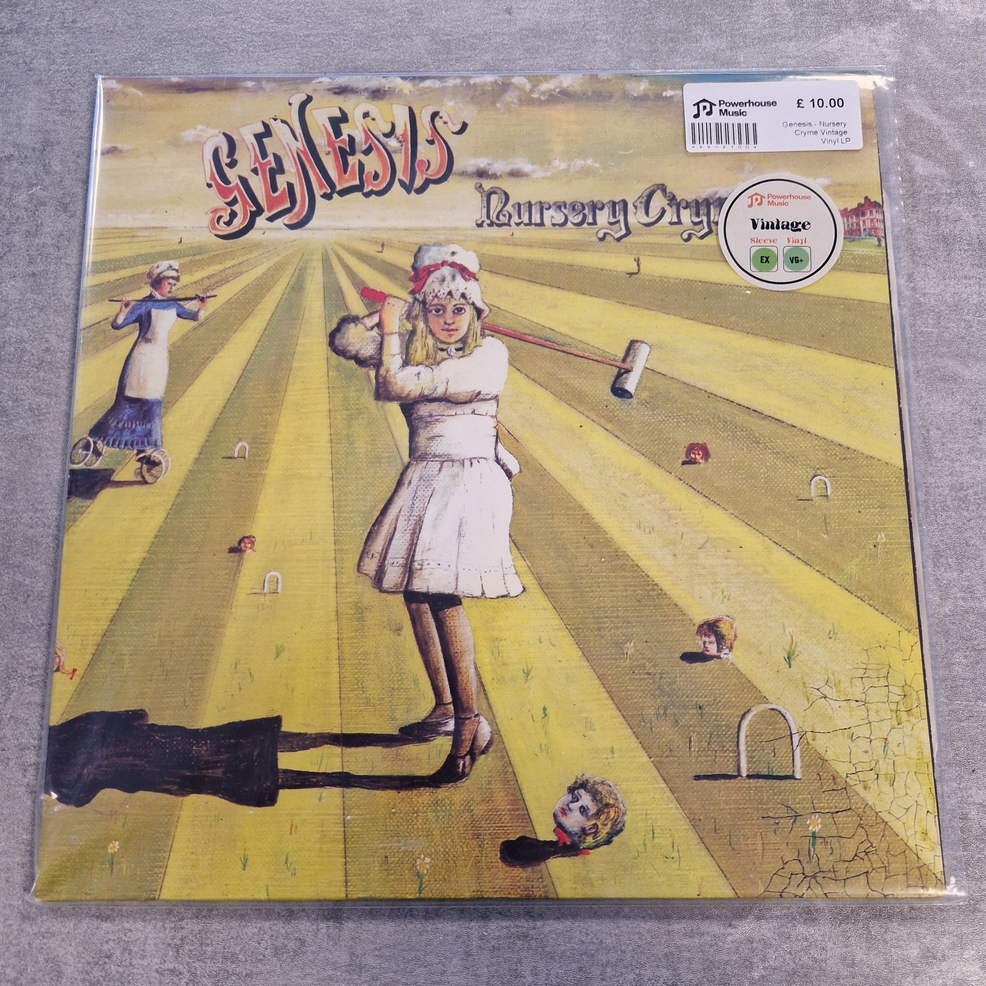 Genesis - Nursery Cryme Vintage Vinyl LP A square printed artwork or album cover shown in a clear plastic sleeve on a gray fabric surface. The artwork features a stylized yellow sunburst background with a woman in a white dress, small floating faces, and decorative text including the word 'Misterioso'.