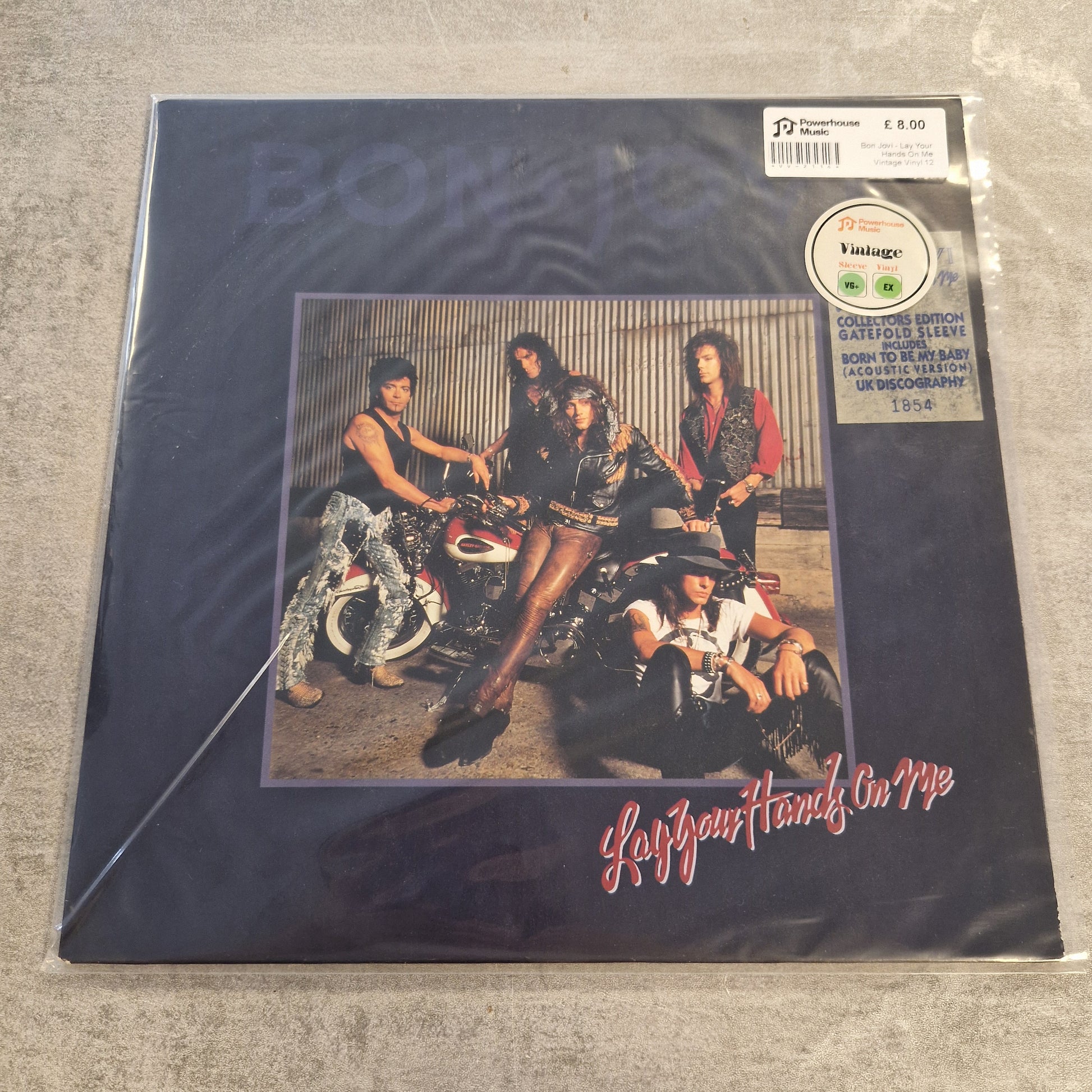 Bon Jovi - Lay Your Hands On Me Vintage Vinyl 12" Single Bon Jovi's 'The Power and the Glory' vinyl record album in its original shrink wrap, photographed on a gray textured floor. The cover is dark blue with the band's name in red script and a central photo of the four band members.