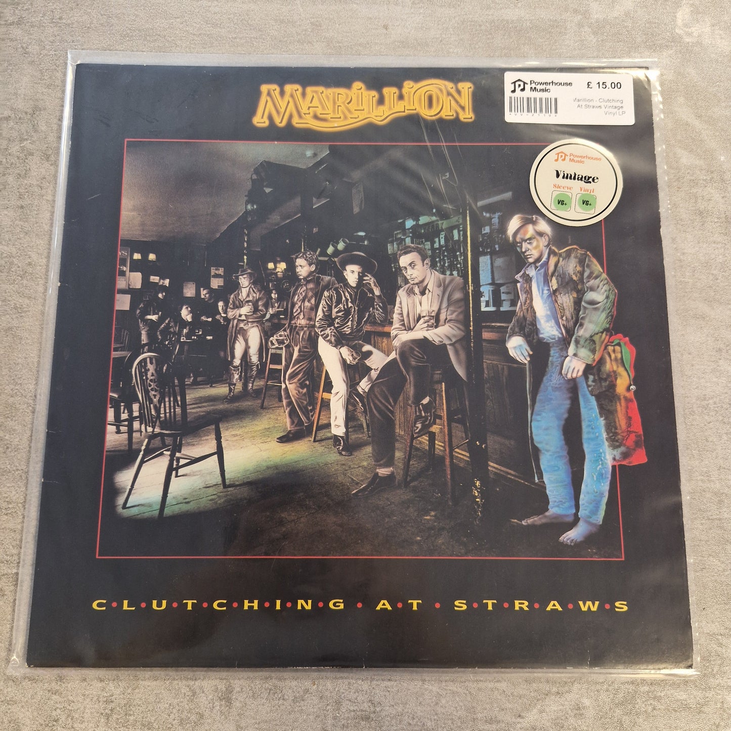 Marillion - Clutching At Straws Vintage Vinyl LP Metal's 'Clutching at Straws' vinyl record sleeve, sealed in plastic with a visible sticker barcode and a green vinyl sticker, placed on a gray textured surface.
