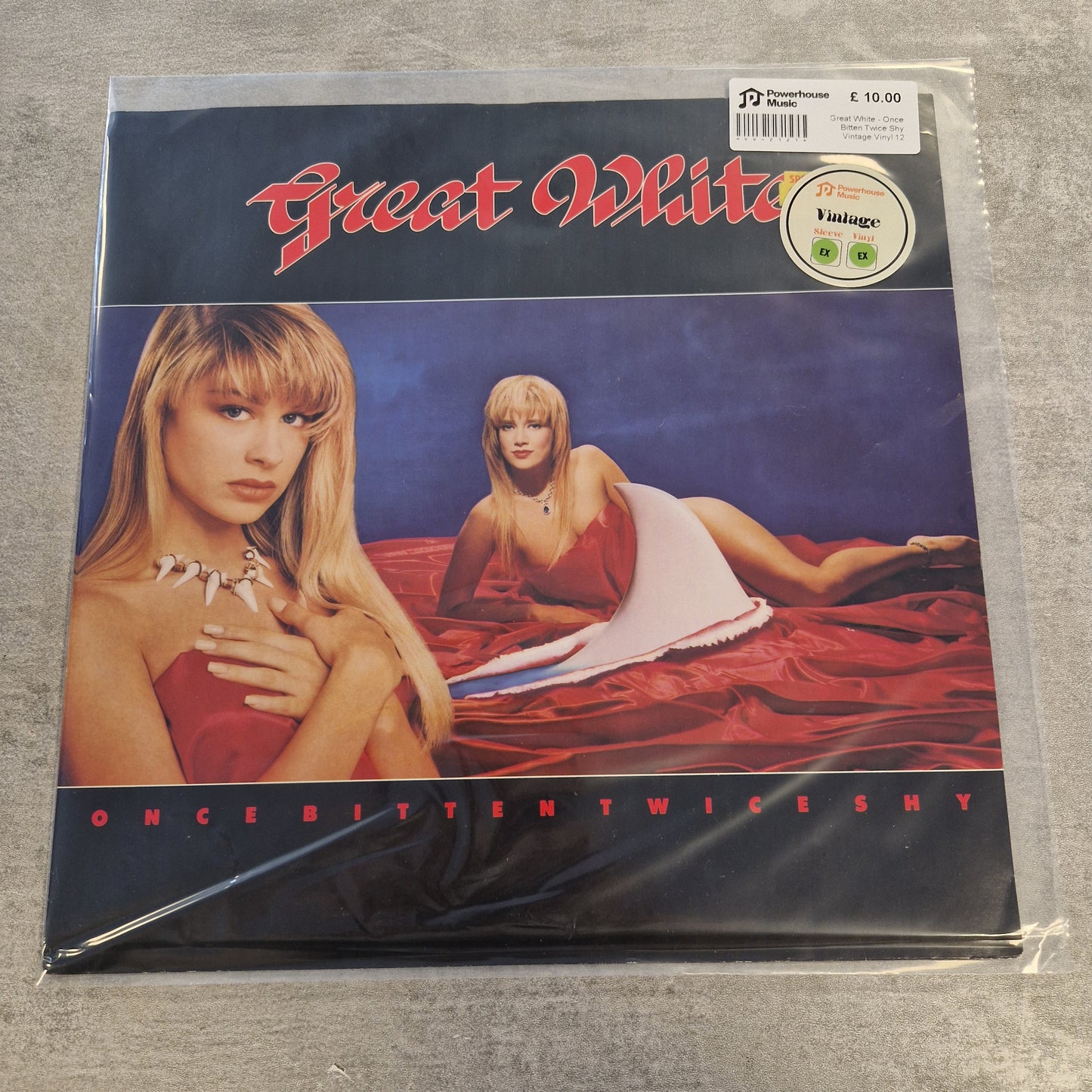 Great White - Once Bitten Twice Shy Vintage Vinyl 12" Single A vinyl record sleeve for Taylor Swift's album 'Fearless (Taylor's Version)' on a gray fabric background, still sealed in its plastic shrink wrap.