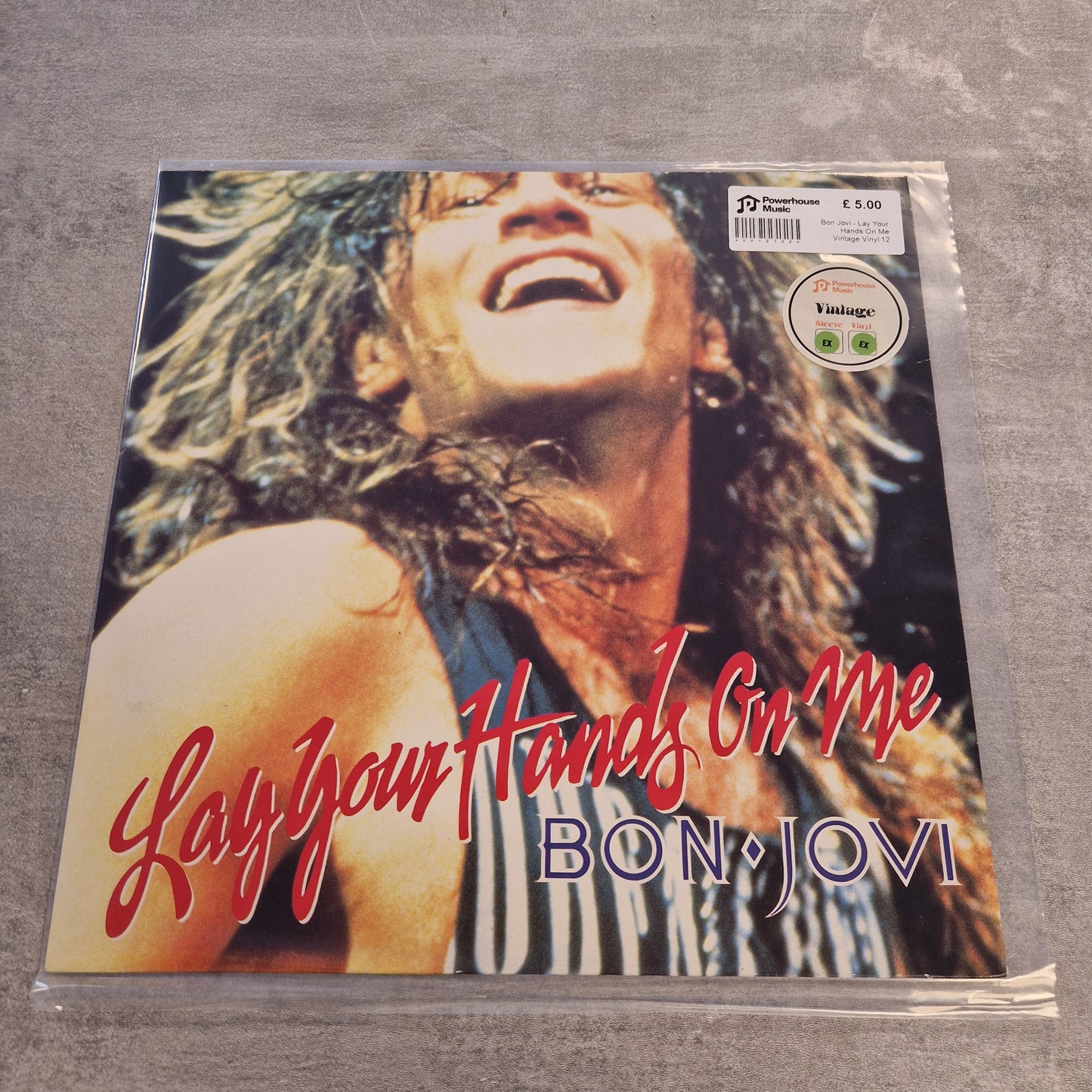Bon Jovi - Lay Your Hands On Me Vintage Vinyl 12" Single Bon Jovi 'Lay Your Hands On Me' vinyl record sleeve in plastic shrink-wrap, photographed against a gray textured background.