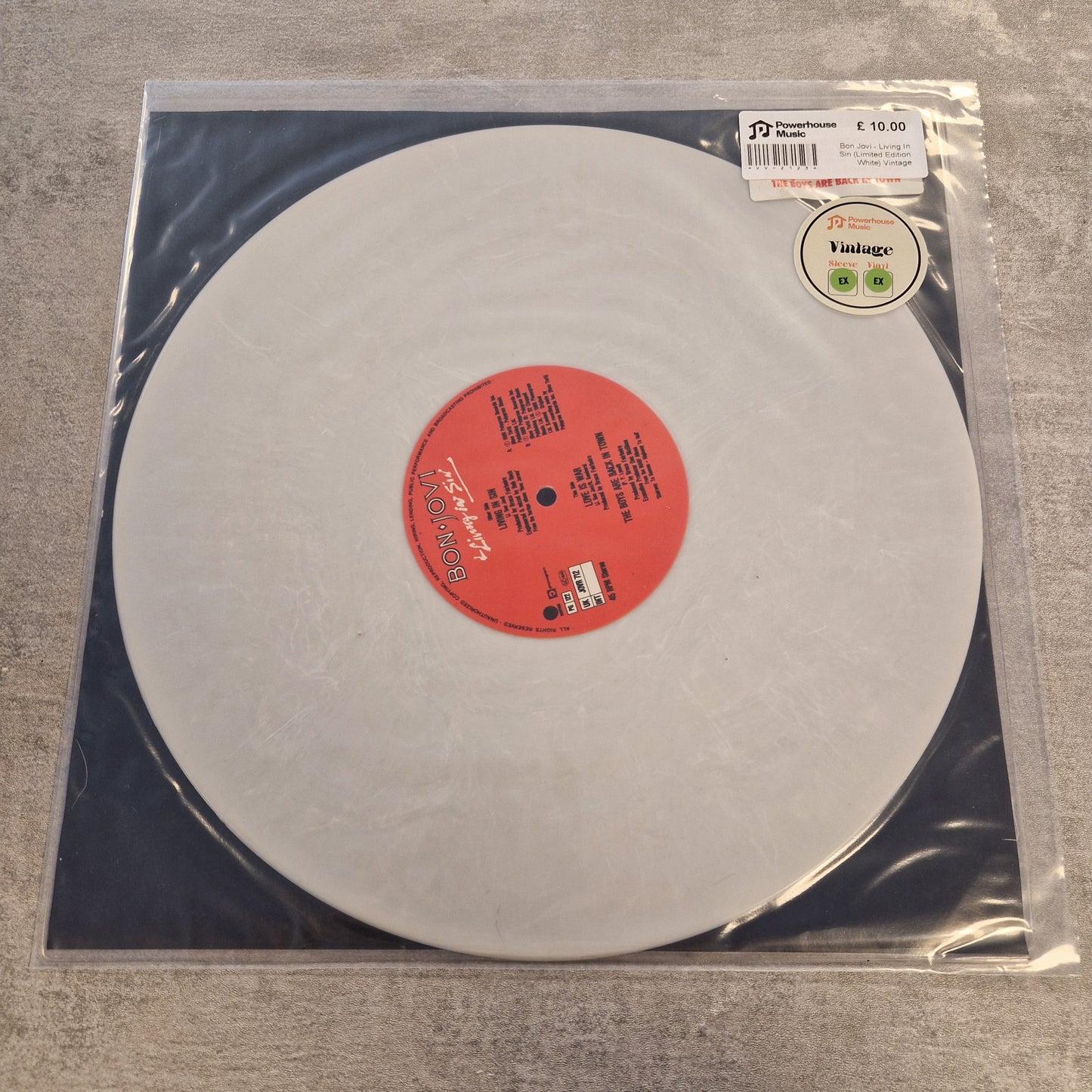 Bon Jovi - Living In Sin (Limited Edition White) Vintage Vinyl 12" Single A white vinyl record in its clear plastic sleeve, featuring a red center label and a barcode sticker on the top left.