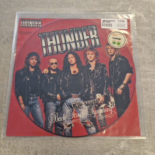 Thunder - Back Street Symphony (Limited Edition Picture Disc) Vintage Vinyl 12" Single A vinyl record sleeve for the band Thunder's 'Back To Hell' album, featuring a red circular design with the band members' photos and a Parental Advisory label, photographed in a clear plastic sleeve on a gray textured surface.