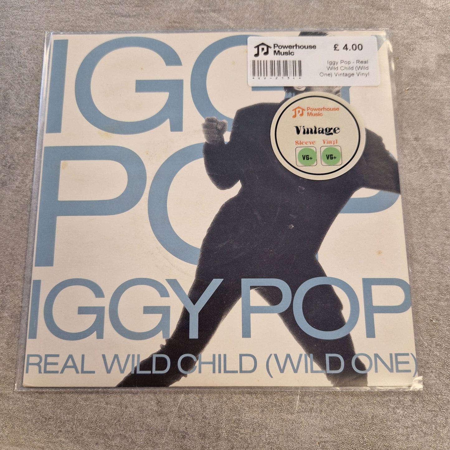 Iggy Pop - Real Wild Child (Wild One) Vintage Vinyl 7" Single A 12-inch vinyl record sleeve for Iggy Pop's 'Real Wild Child (Wild One)' on Powerhouse Music, sealed in a protective plastic sleeve. The cover features a large light blue 'IGGY POP' logo and a black silhouette of a child against a white background.