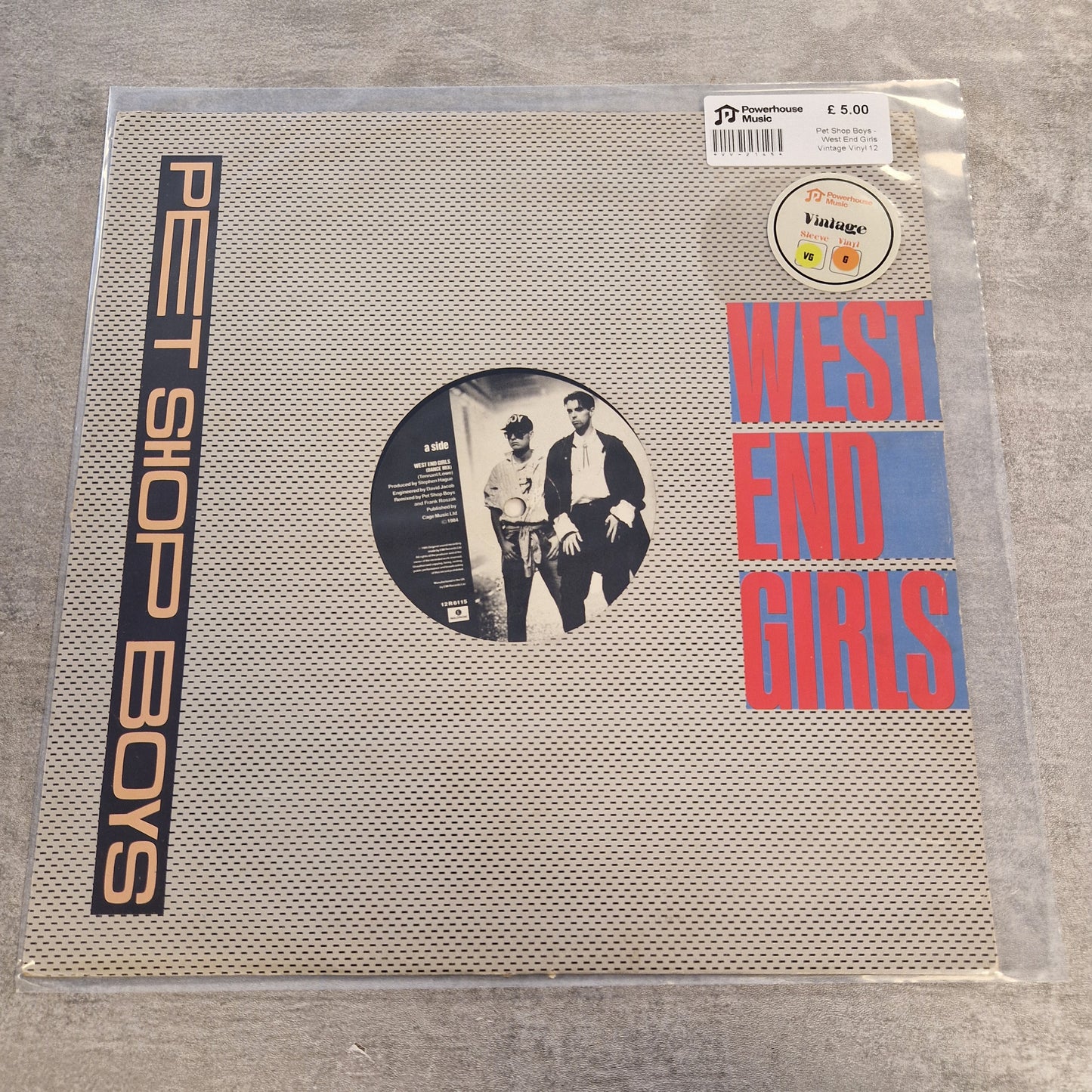 Pet Shop Boys - West End Girls Vintage Vinyl 12" Single West End Girls vinyl record album in a clear plastic protective sleeve, featuring the band's name in large red and blue letters at the top and 'PET SHOP BOYS' in orange text at the bottom, with a circular black-and-white photo in the center.