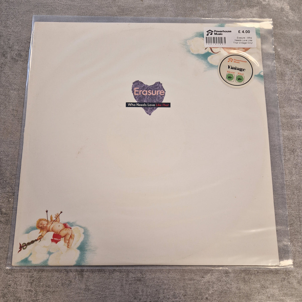 Erasure - Who Needs Love Like That Vintage Vinyl 12" Single A vinyl record sleeve for Erasure's 'All Around Love' 12-inch release, sealed in a clear plastic protective case. The sleeve features a clean white background with a purple heart-shaped logo in the center and cherub illustrations in the bottom-left corner.
