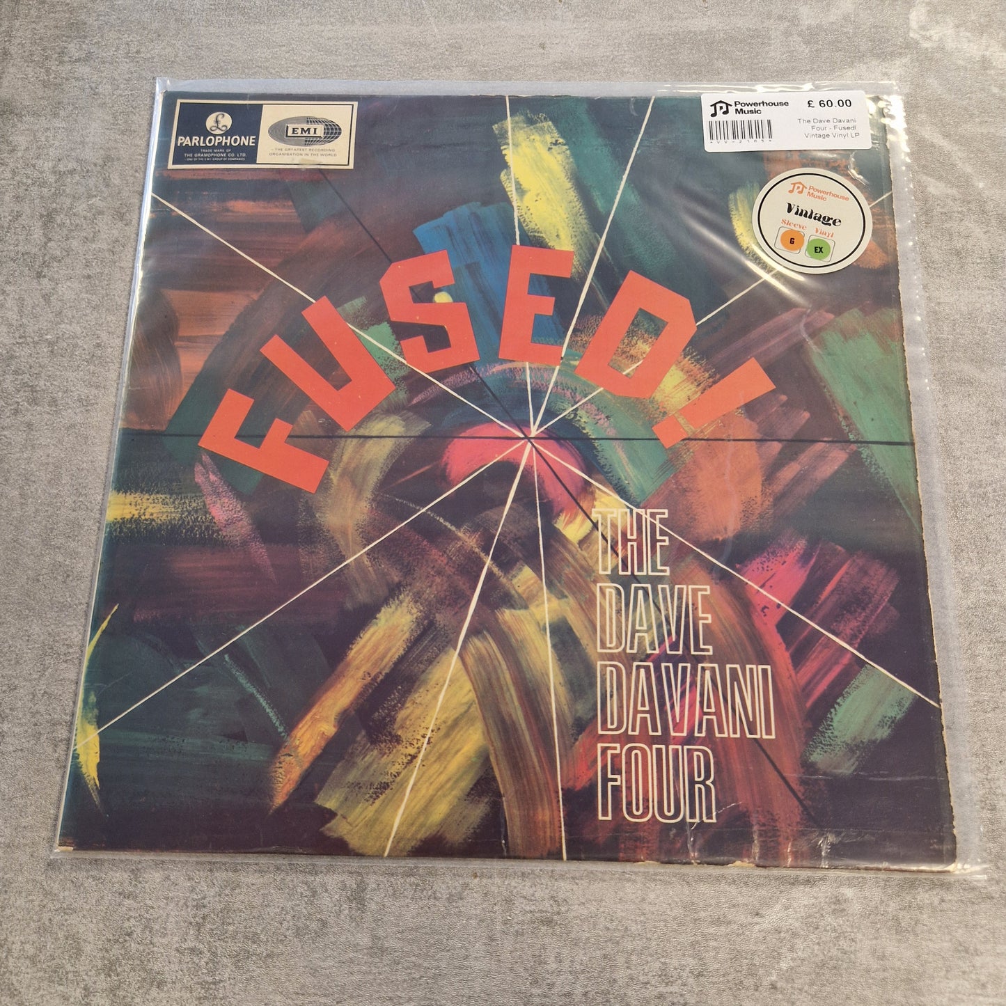 The Dave Davani Four - Fused! Vintage Vinyl LP A vinyl record sleeve for Dave Davies' album 'Fused!' lies on a gray textured surface. The sleeve features a colorful abstract painted background with the title 'FUSED!' in large orange-red letters and 'THE DAVE DAVIES FOUR' in white text.