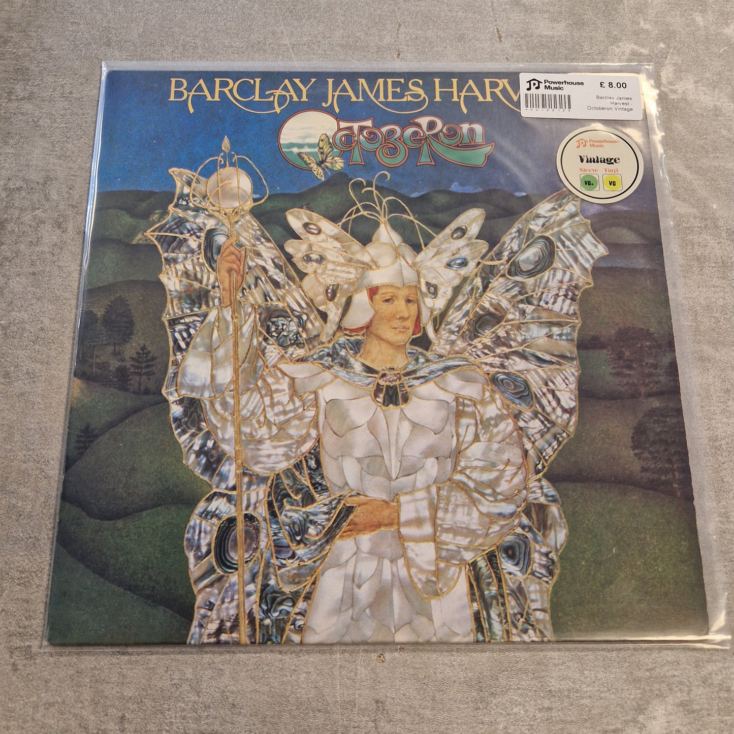 Barclay James Harvest - Octoberon Vintage Vinyl LP Barclay James Harriott's 'Fog Roll' vinyl record album in its original shrink wrap, displayed on a gray textured surface. The cover art features a detailed illustration of a winged figure in white and silver armor against a dark blue sky and green hills.