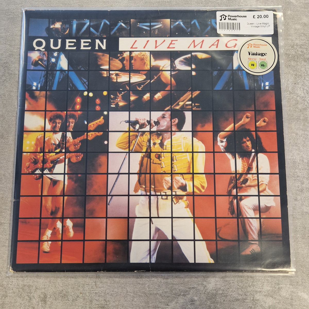 Queen - Live Magic Vintage Vinyl LP Queen 'Live Mag' vinyl record sleeve on a gray surface, featuring a collage of concert photos in a grid pattern with a barcode sticker and a Vintage logo.