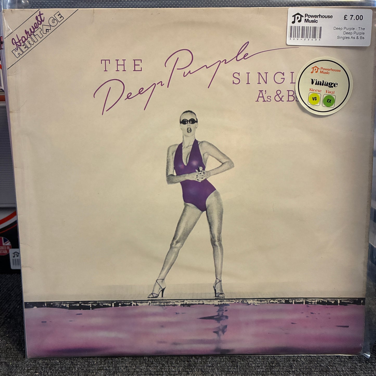 Deep Purple - The Deep Purple Singles A's & B's Vintage Vinyl LP The Deep Purple 'Single As & B' vinyl record album cover, showing a vintage-style illustration of a woman in a purple swimsuit on a cream background with a purple reflective waterline at the bottom. A JD Powerhouse Music sticker is visible in the top right corner.