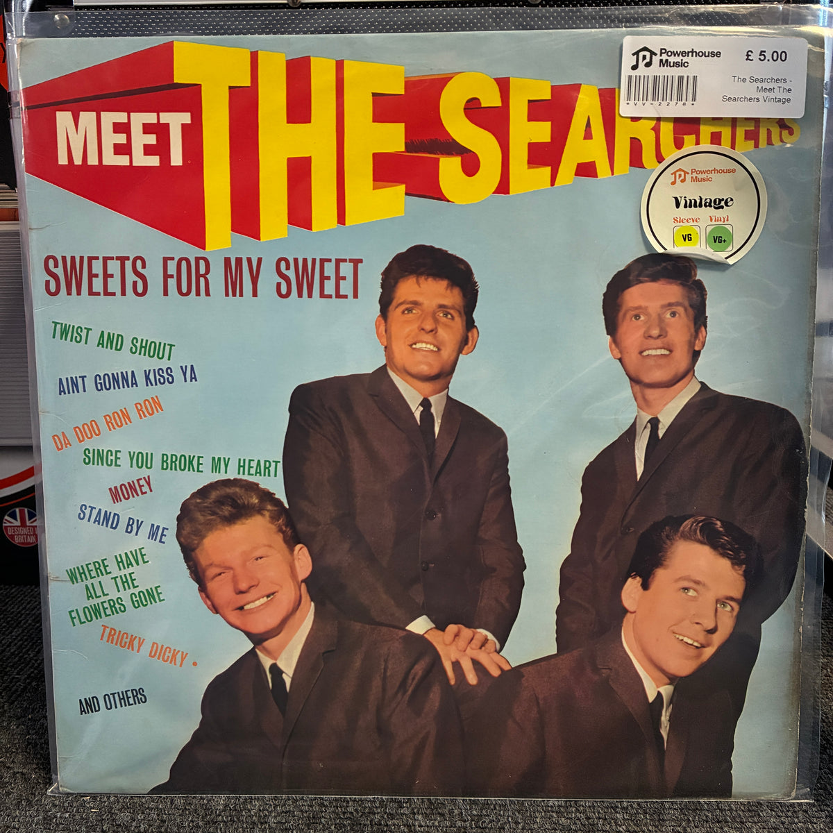 The Searchers - Meet The Searchers Vintage Vinyl LP A vinyl record sleeve for 'Meet The Searchers - Sweets For My Sweet' on a clear plastic sleeve, photographed flat. The cover features the band members in suits against a light blue background with bold yellow and red title text.