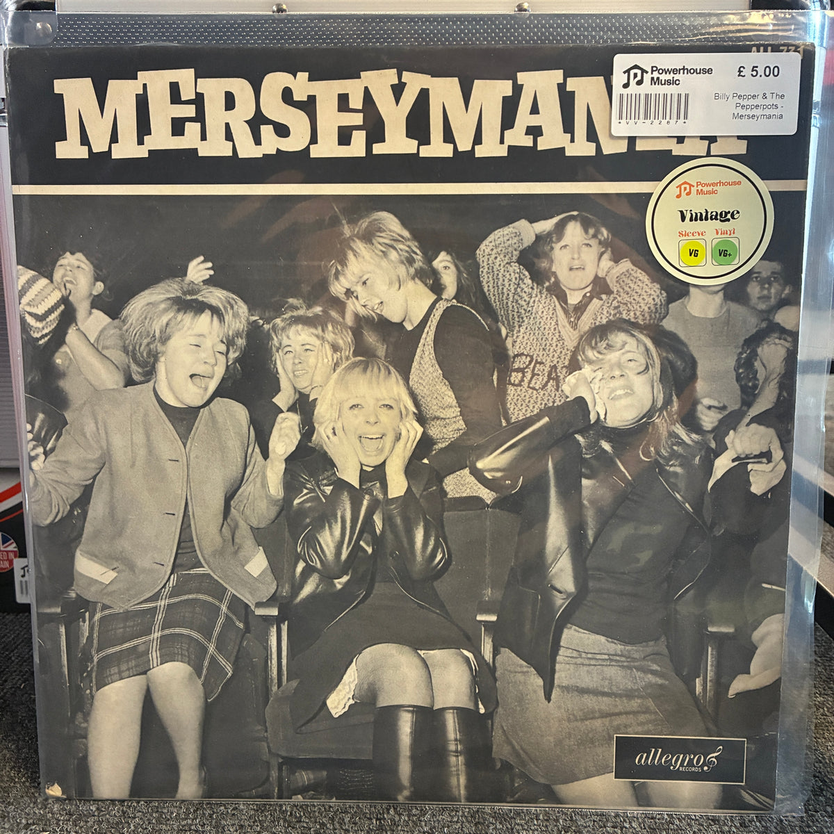 Billy Pepper & The Pepperpots - Merseymania Vintage Vinyl LP Merseyman '76 vinyl record cover for '76, featuring a black and white photo of a crowd with the title 'MERSEYMAN '76' in large cream letters. Includes a Powerhouse Music sticker and a Vintage Vinyl sticker, photographed in a clear plastic sleeve.