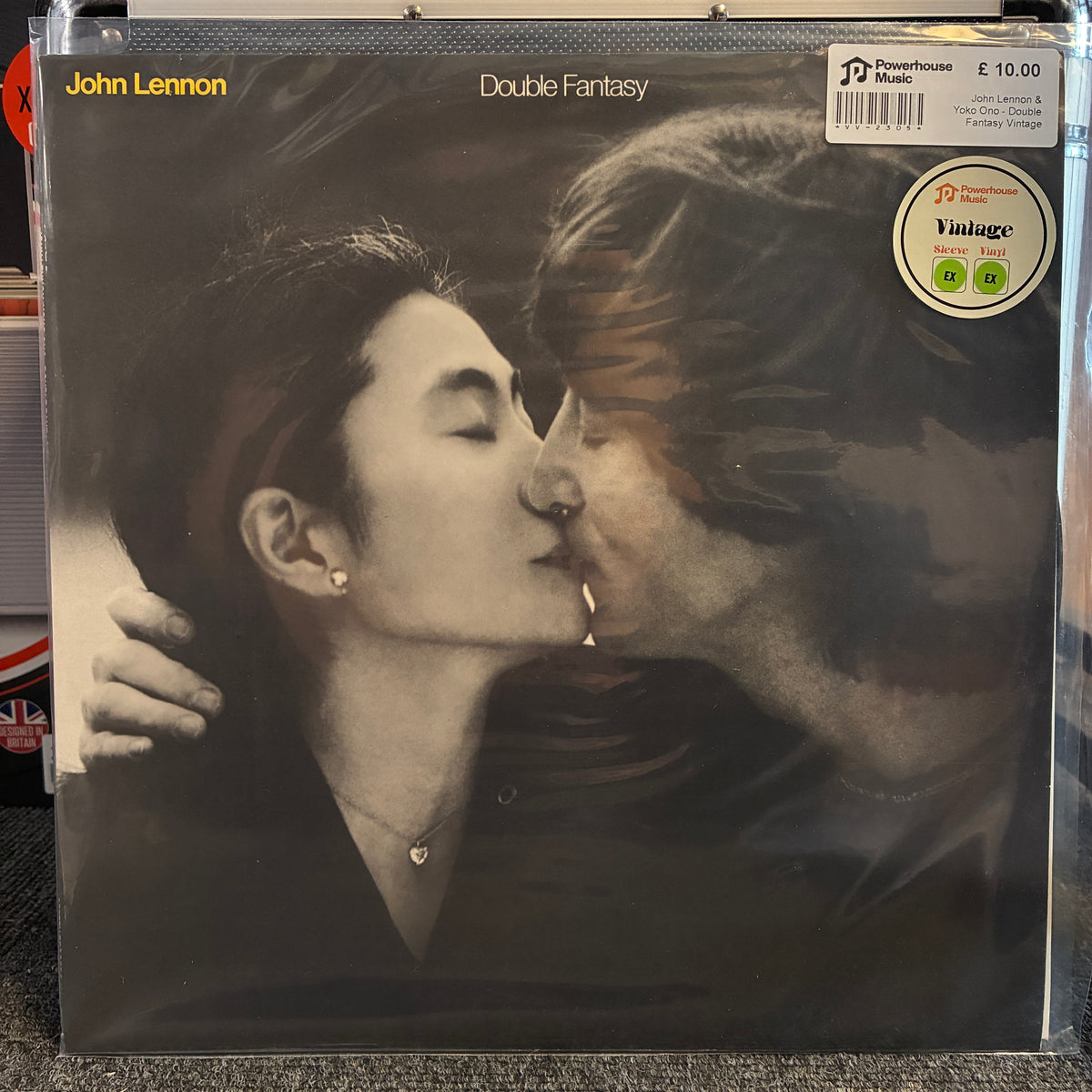 John Lennon & Yoko Ono - Double Fantasy Vintage Vinyl LP A John Lennon 'Double Fantasy' vinyl record sleeve in plastic shrink-wrap, photographed from above on a carpeted floor. The cover is black-and-white with a kiss between the two figures, and visible stickers include a PriceWaterhouse Music price label and a Vintage Records sticker.