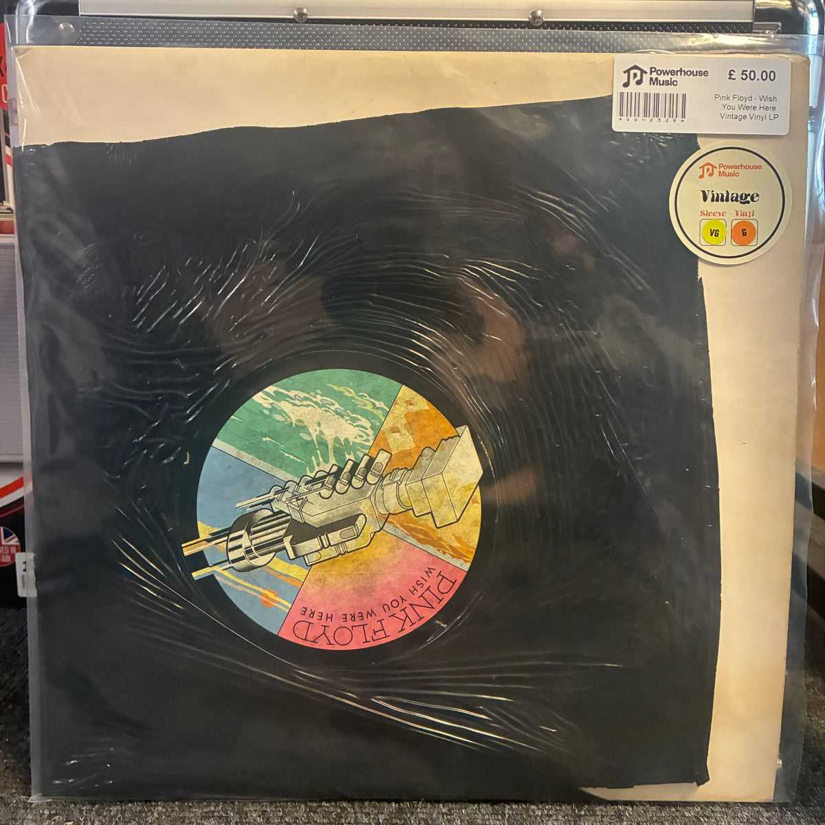 Pink Floyd - Wish You Were Here Vintage Vinyl LP Pink Floyd 'The Dark Side of the Moon' vinyl record in its original paper sleeve, sealed in protective plastic. The cover features the iconic black vinyl disc graphic with the multicolored album art in the center, set against a cream-colored background.