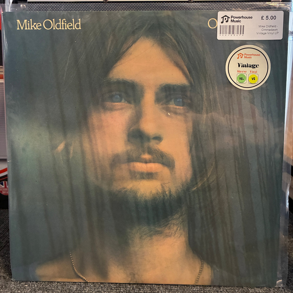 Mike Oldfield - Ommadawn Vintage Vinyl LP Mike Oldfield 'Omen' vinyl record LP cover, sealed in a protective plastic sleeve. The cover features a close-up portrait of the artist with a dark, moody background.