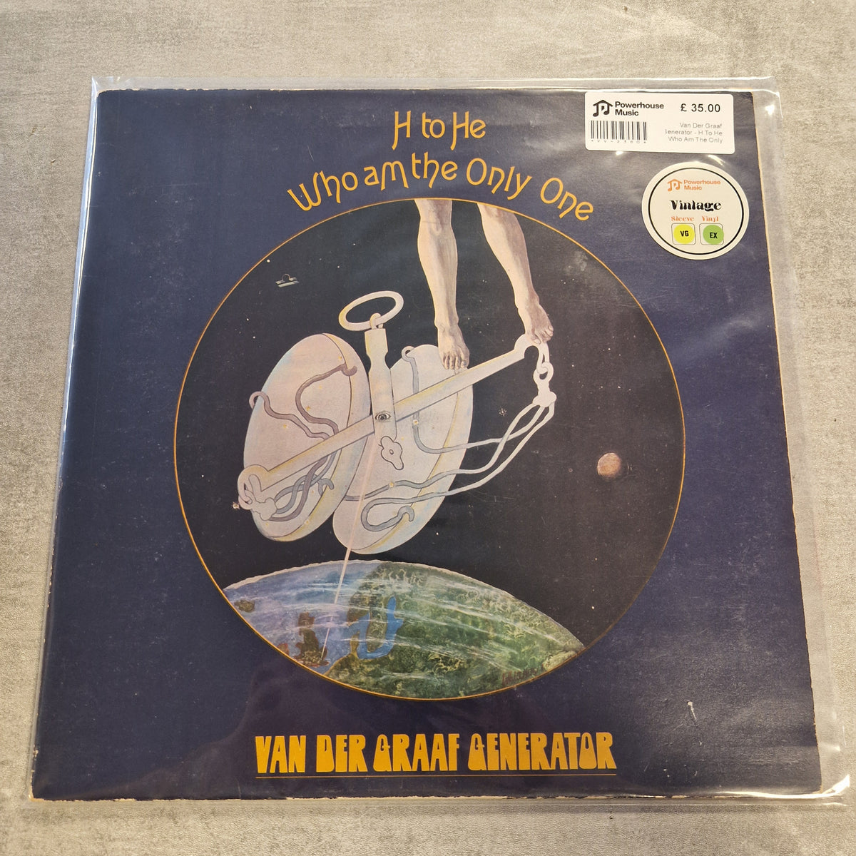 Van Der Graaf Generator - H To He Who Am The Only One Vintage Vinyl LP A vinyl record sleeve for Van der Graaf Generator's album 'H to He Who am the Only One', featuring a dark blue cover with a circular illustration of legs and a globe, photographed on a gray surface with a barcode sticker and a vintage logo visible.