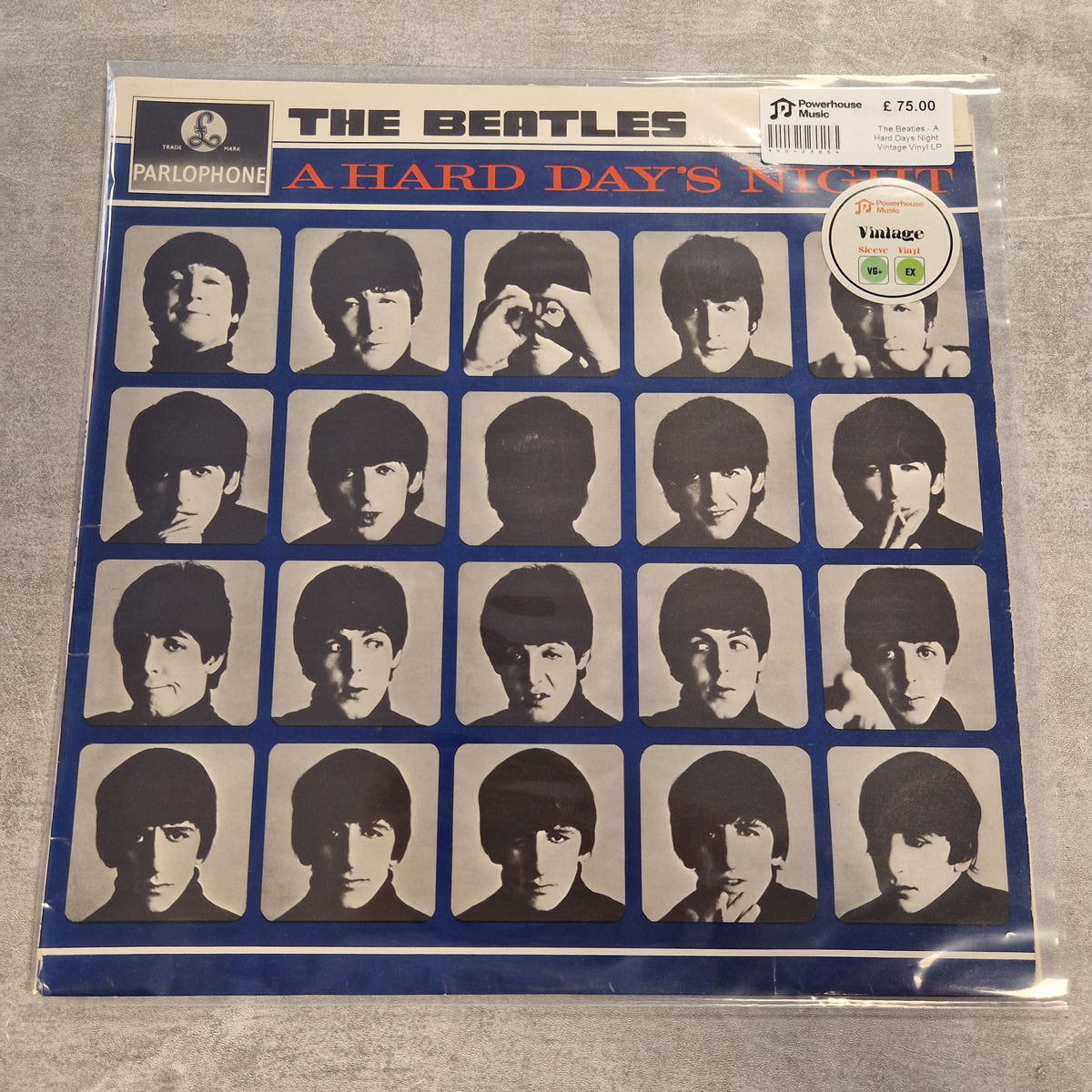 The Beatles - A Hard Days Night Vintage Vinyl LP A Parlophone vinyl record of The Beatles' 'A Hard Day's Night' in its original blue sleeve, sealed in a protective plastic bag. The cover features a grid of black and white portraits of the band members.