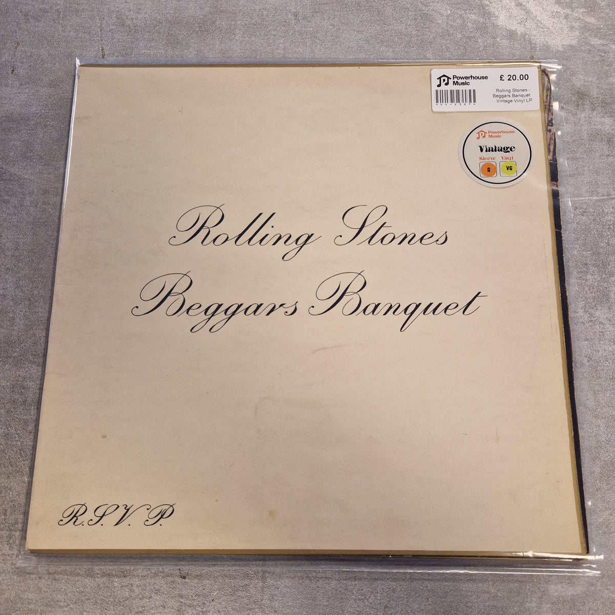Rolling Stones - Beggars Banquet Vintage Vinyl LP Rolling Stones - Reggars Banquet vinyl record album cover in its original shrink wrap, displayed on a gray textured surface. The cover is a warm cream color with elegant black cursive text, featuring a small 'Vintage' sticker and a price sticker in the top right corner.