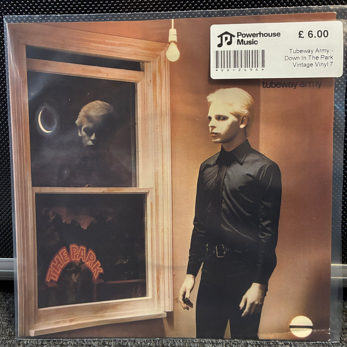 Tubeway Army - Down In The Park Vintage Vinyl 7" Single A vinyl record sleeve for Tubeway Army's 'Down In The Park' on the 'Vintage Vinyil7' label, featuring a white Powerhouse Music sticker on the top right. The artwork shows a blonde man in a black shirt standing next to a window with a dark, surreal scene inside.