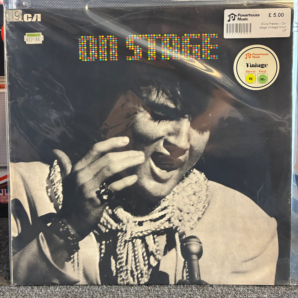 Elvis Presley - On Stage Vintage Vinyl LP A vintage 12-inch vinyl record of Elvis Presley's 'On Stage' LP, sealed in its original plastic shrink wrap. The cover features a black-and-white portrait of Elvis with colorful LED-style text reading 'ON STAGE'.