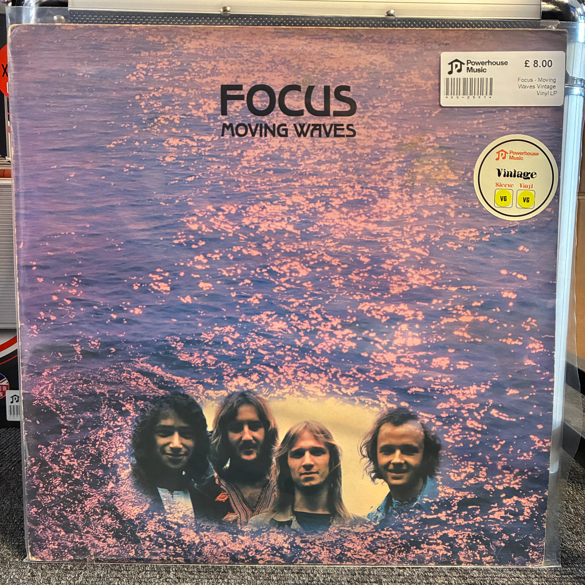 Focus - Moving Waves Vintage Vinyl LP A vinyl record sleeve for the band Focus's album 'Moving Waves', featuring a purple-toned water scene with pink cherry blossoms and the band members' portraits at the bottom. A 'Vintage Condition' sticker is visible in the top right corner.