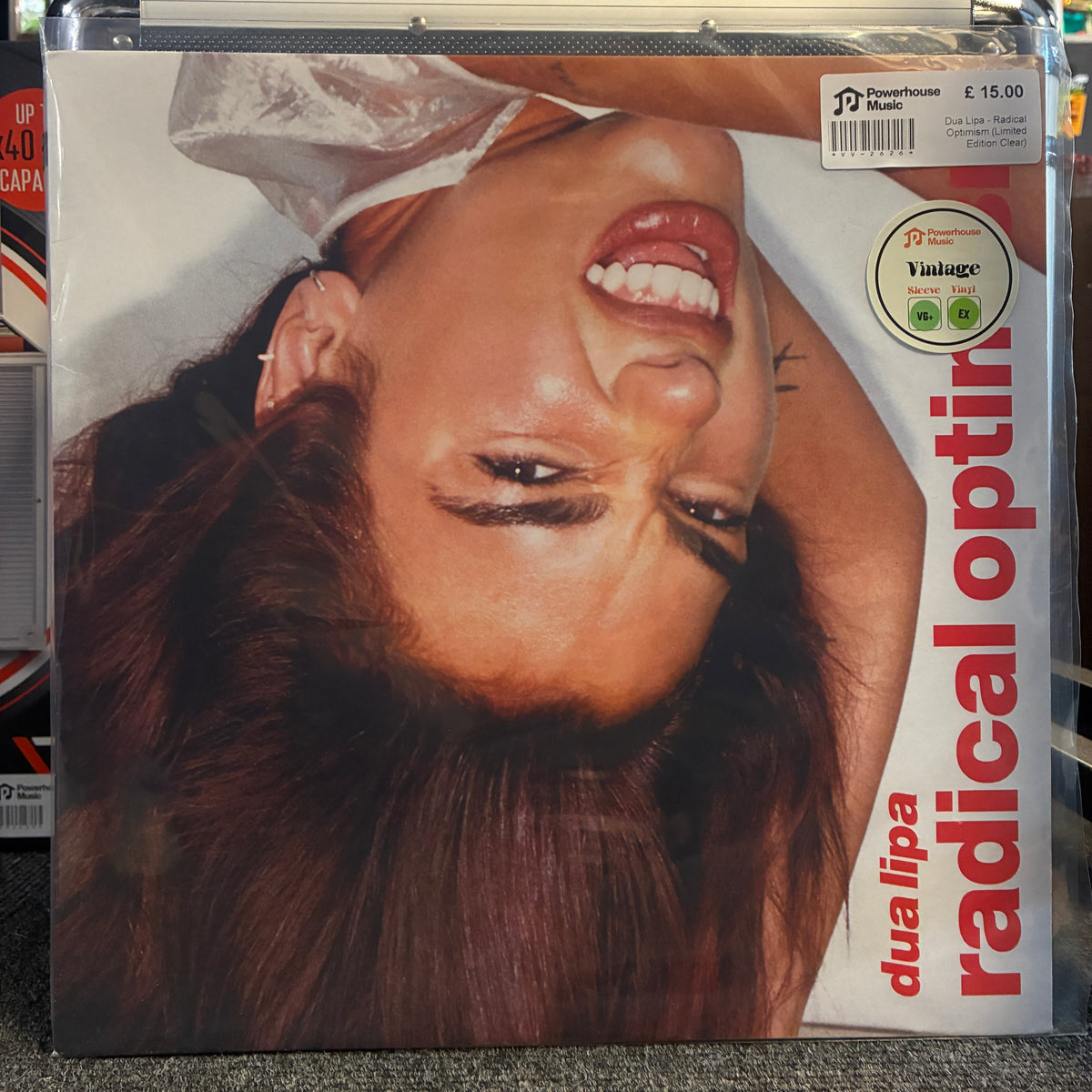 Dua Lipa - Radical Optimism (Limited Edition Clear) Vintage Vinyl LP A vinyl record sleeve for 'radical optimist' by duo lipa, featuring a close-up photo of a smiling woman with dark hair. The sleeve is inside a clear plastic protective case, with a barcode sticker and a 'Vintage' label visible on the cover.