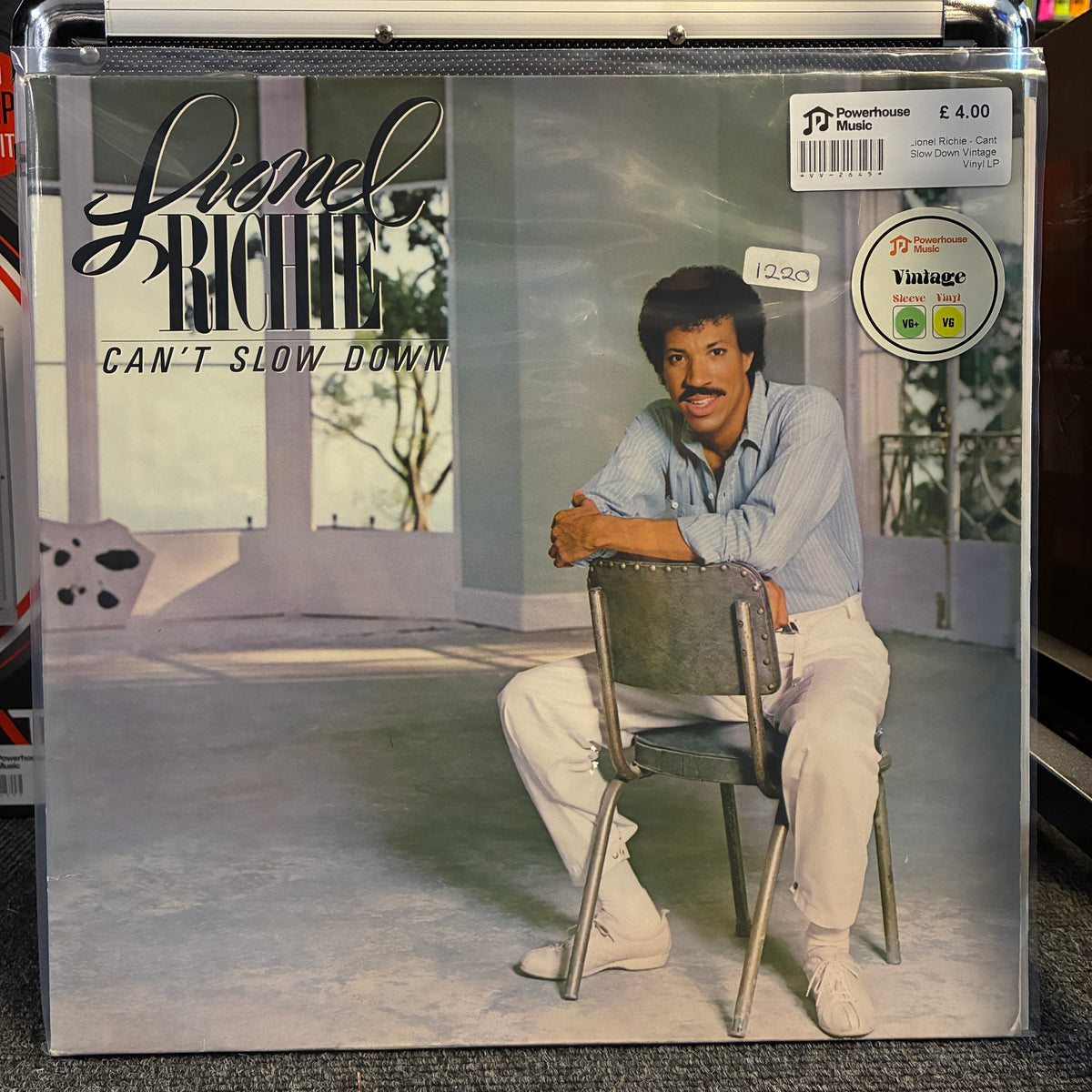 Lionel Richie - Can't Slow Down Vintage Vinyl LP Lionel Richie 'Can't Slow Down' vinyl record cover inside a clear protective case, photographed on a dark surface. The cover shows Lionel Richie seated on a chair in a bright interior, with the Powerhouse logo and a Vintage logo visible on the cover and sticker area.