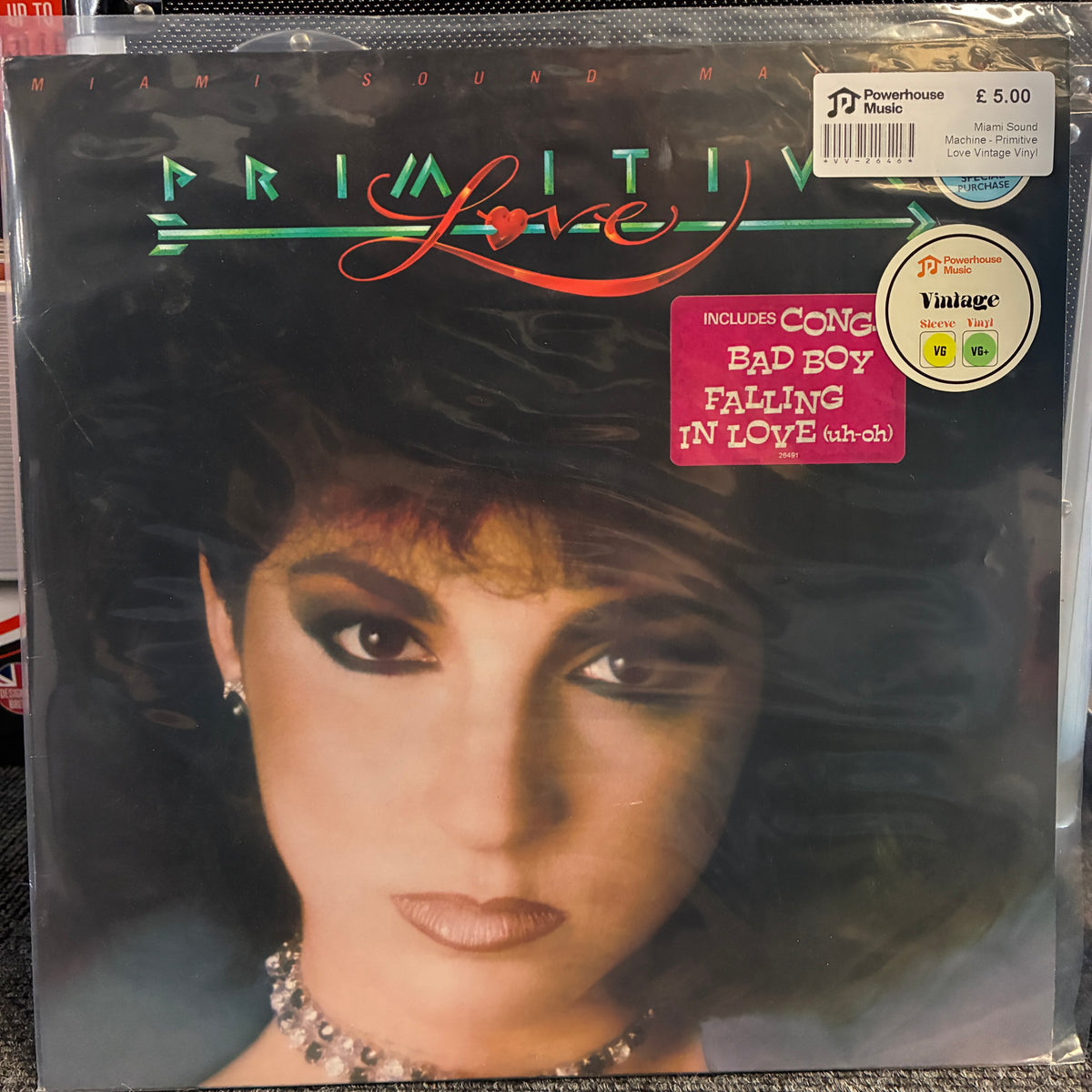 Miami Sound Machine - Primitive Love Vintage Vinyl LP A sealed vinyl record sleeve for the album 'Love' by the band Primitiv, featuring a close-up portrait of a woman with dark hair and dramatic eye makeup. The cover has a pink sticker listing included tracks, a barcode price sticker in the top right, and the record label 'Powerhouse' visible.