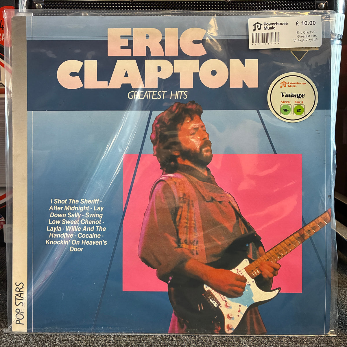Eric Clapton - Greatest Hits Vintage Vinyl LP Eric Clapton Greatest Hits vinyl record album in its original shrink wrap, featuring a blue cover with a pink square and a photo of Eric Clapton playing an electric guitar.