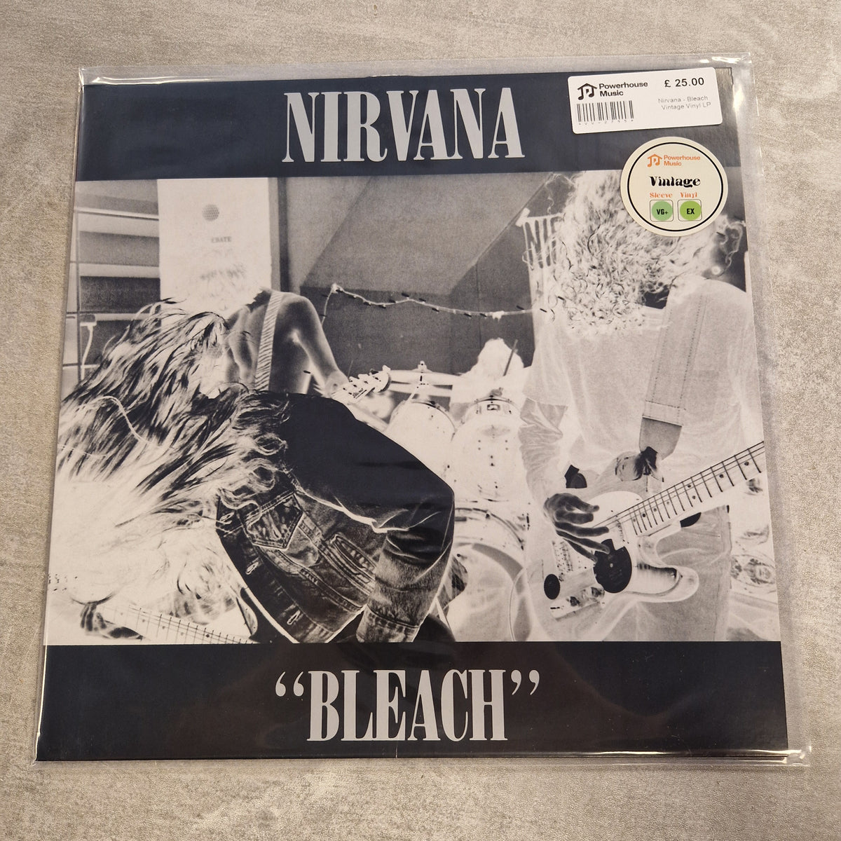 Nirvana - Bleach Vintage Vinyl LP Nirvana Bleach vinyl record sleeve in clear plastic shrink wrap, photographed on a light gray textured surface. The cover is black-and-white with the band name 'NIRVANA' at the top and the title 'BLEACH' at the bottom.