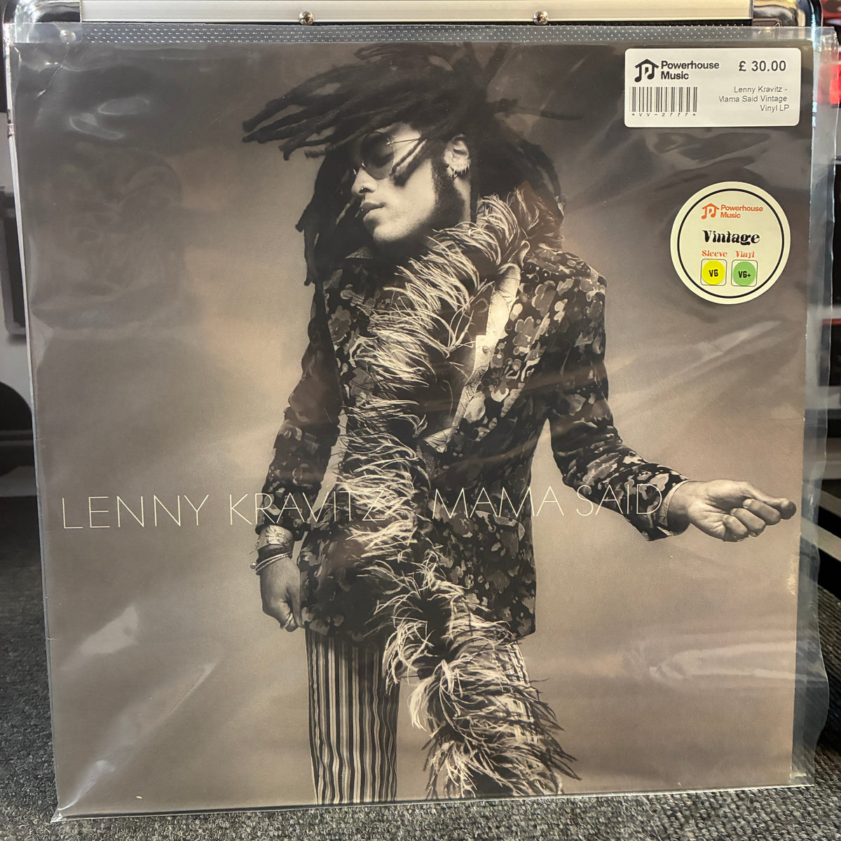 Lenny Kravitz - Mama Said Vintage Vinyl LP A vinyl record sleeve for Lenny Kravitz's 'Mama Said' on a clear plastic shrink wrap, photographed on a gray carpet. The cover art is monochrome sepia-toned, featuring a portrait of Lenny Kravitz in sunglasses and a feathered jacket.