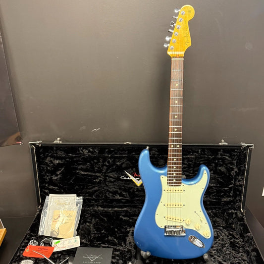 Pre-Owned Fender Blue electric guitar with a yellow pickguard on a black case against a grey background