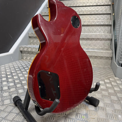 Pre-Owned Gibson Les Paul Classic '1960' 2001 Electric - Cherry Sunburst A red electric guitar body, likely a Gibson Les Paul style, displayed on a black stand on a diamond-plate metal staircase.