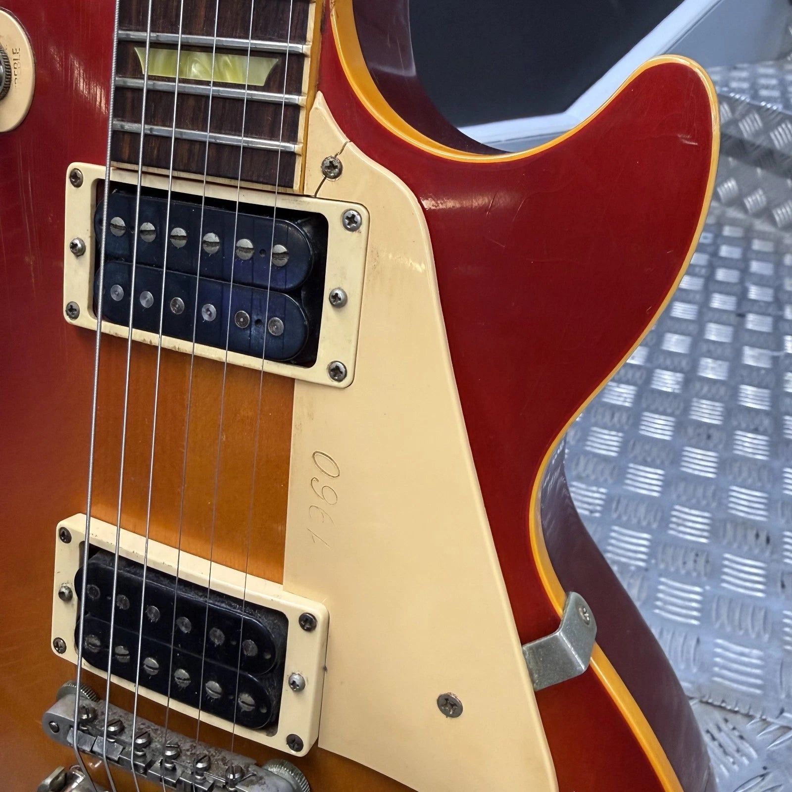 Pre-Owned Gibson Les Paul Classic '1960' 2001 Electric - Cherry Sunburst Close-up of a classic electric guitar body showing a red sunburst finish, cream-colored pickguard, black humbucker pickups, and a yellow outline accent.