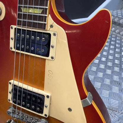 Pre-Owned Gibson Les Paul Classic '1960' 2001 Electric - Cherry Sunburst Close-up of a classic electric guitar body showing a red sunburst finish, cream-colored pickguard, black humbucker pickups, and a yellow outline accent.