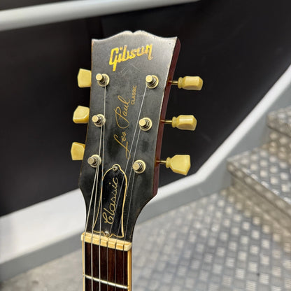 Pre-Owned Gibson Les Paul Classic '1960' 2001 Electric - Cherry Sunburst Close-up of a Gibson Les Paul Classic electric guitar headstock, showing the gold Gibson logo, 'Les Paul Classic' script, and six gold tuning pegs on a dark wood headstock.