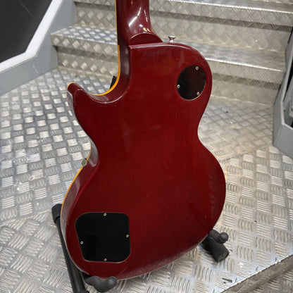 Pre-Owned Gibson Les Paul Classic '1960' 2001 Electric - Cherry Sunburst The rear view of a Gibson Les Paul Custom electric guitar in a glossy dark red finish, resting on a black guitar stand on a diamond plate metal surface.