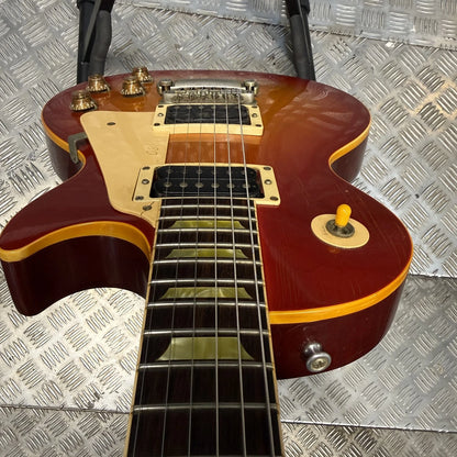 Pre-Owned Gibson Les Paul Classic '1960' 2001 Electric - Cherry Sunburst A double-cutaway electric guitar with a glossy dark red sunburst finish, cream pickguard, and gold hardware, photographed from above on a diamond plate metal surface.