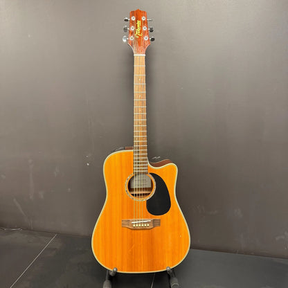 Pre-Owned Takamine EG530SC Acoustic guitar on a stand against a grey wall