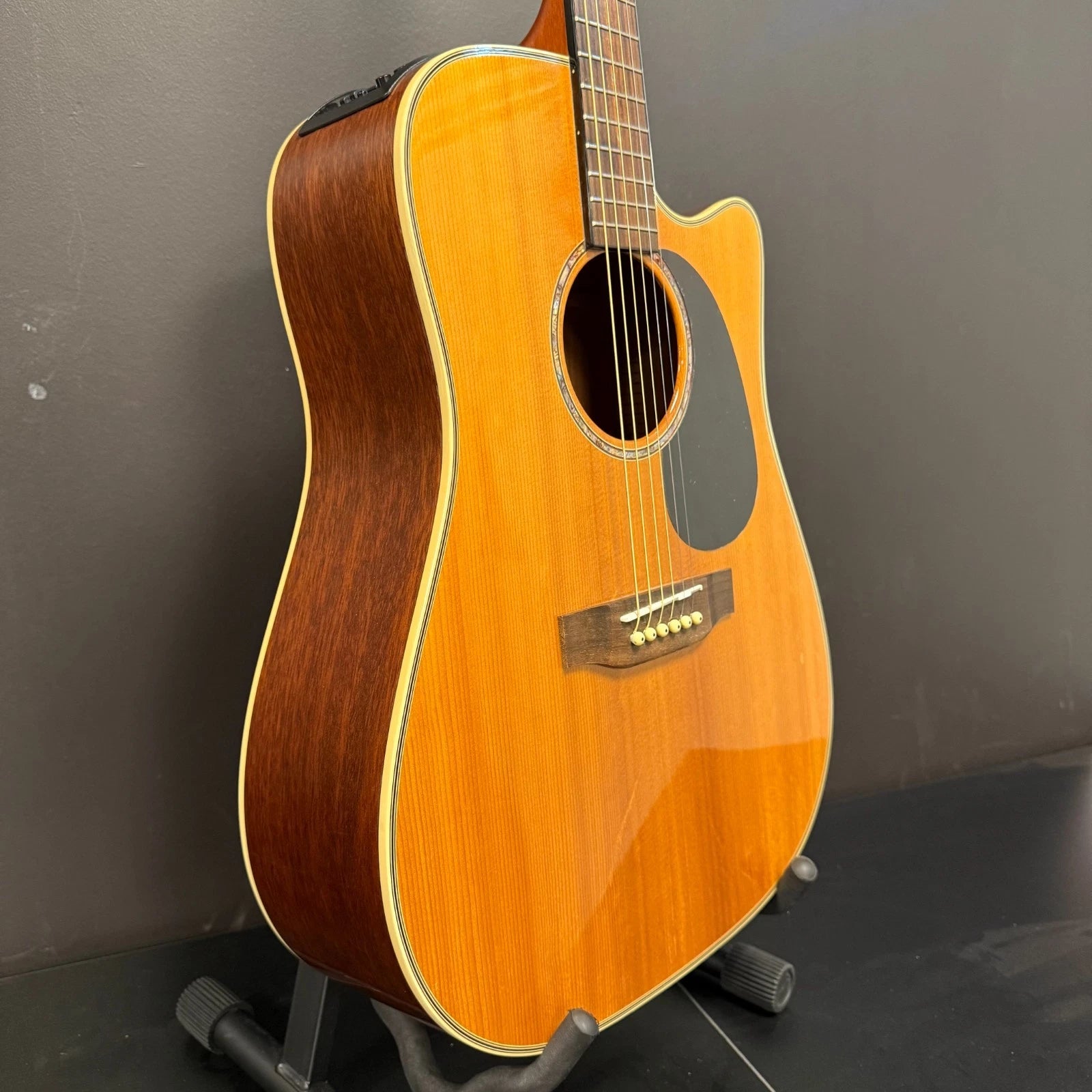 Pre-Owned Takamine EG530SC Acoustic guitar on a stand against a dark background
