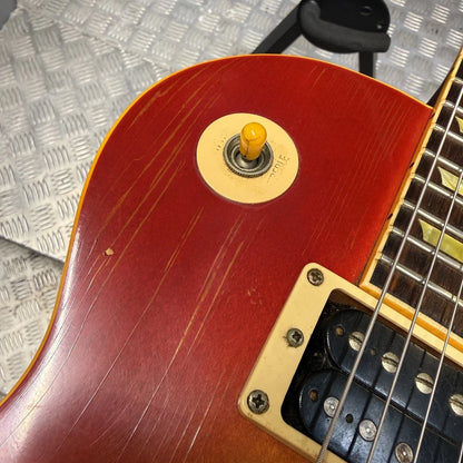 Pre-Owned Gibson Les Paul Classic '1960' 2001 Electric - Cherry Sunburst Close-up of a red electric guitar body showing a circular gold switch with a yellow knob, part of the gold pickguard, and the fretboard.