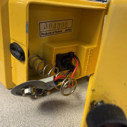 Pre-Owned Boss OD-1 Close-up of a yellow mechanical device with visible springs and wiring on a gray surface.
